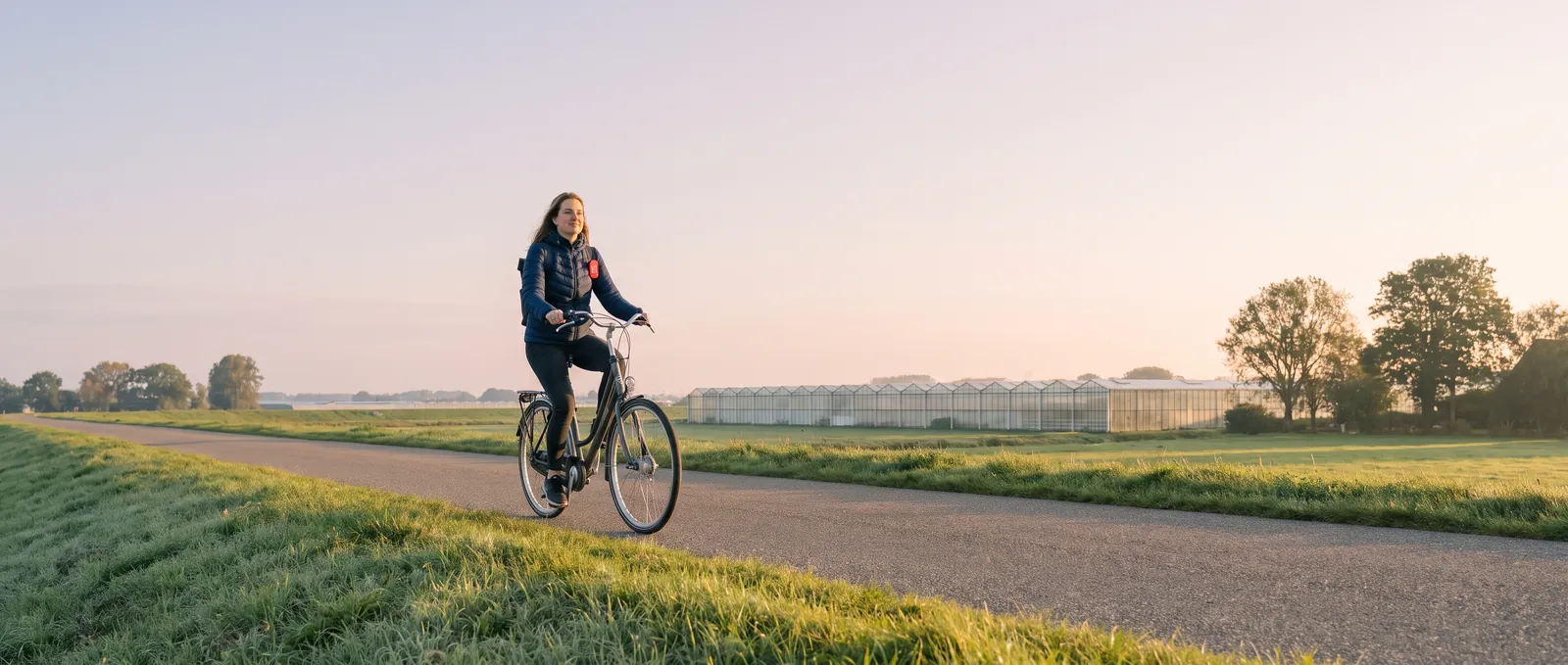 Medewerker fietst bij zonsopkomst naar de kassen